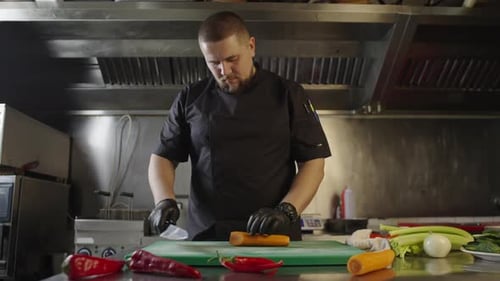 The Chef Cuts Carrots in the Kitchen at the Restaurant