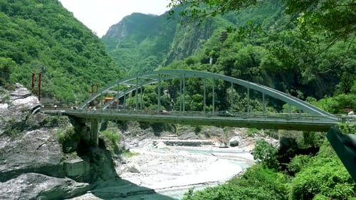 The iron bridge in the valley. There are cars and passengers on the bridge.