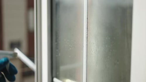 Ein Mann in Handschuhen wäscht ein Fenster in einer Wohnung zu Hause Sauberkeit und Gesundheit Hausarbeit