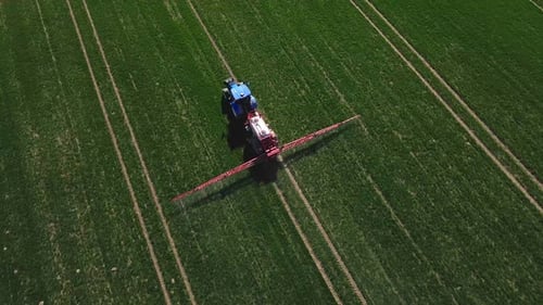 Tractor Spraying Fertilizer on Green Crop Field Aerial View