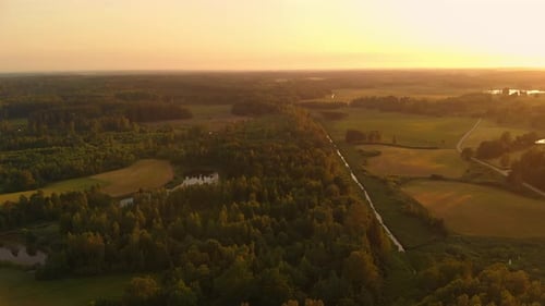 Land of forest and agriculture during golden hour, aerial drone view