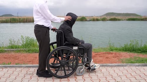 Disabled man in a wheelchair and his brother in the park.