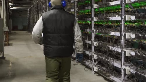 Data Center Diagnostics Technician Walks Along the Mining Equipment Racks in Server Room Network