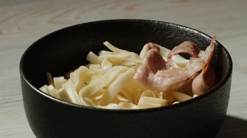 Noodles and Meat Being Placed in Bowl