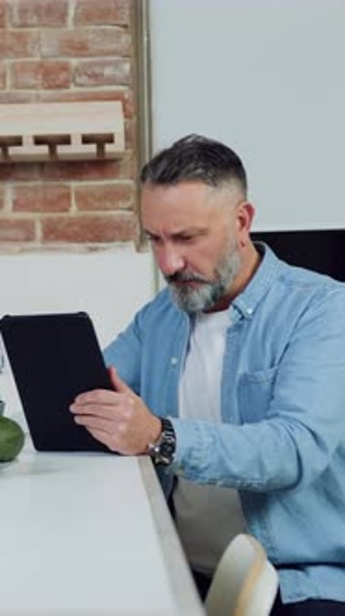 Man Using Tablet Device at Kitchen Table Indoors
