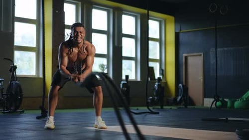 Fit Man Doing Battle Rope Exercise in Gym