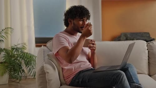 Man Eating with Laptop on Couch Indoors