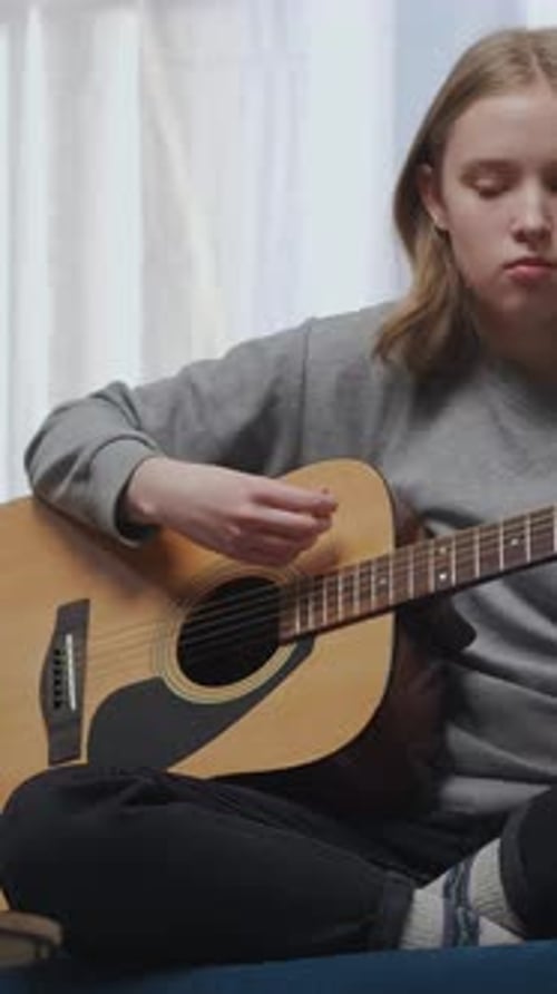 Teen Girl Plays Acoustic Guitar in Relaxing Home Setting