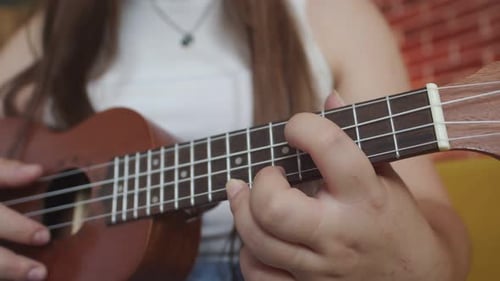 Woman Playing a Brown Ukulele Close Up