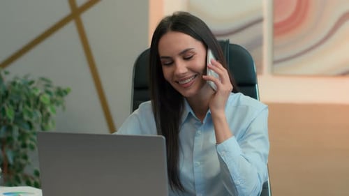 Woman Talking on Phone and Using Laptop in Office