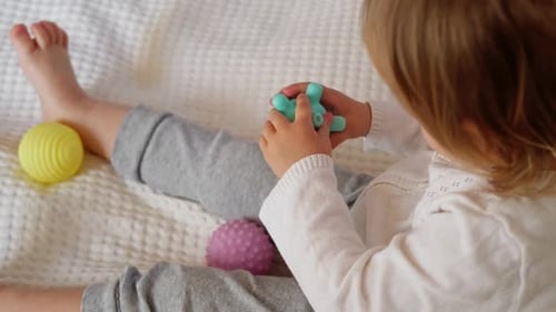 Child Plays with Colorful Textured Balls on Blanket
