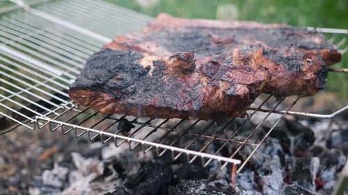 In Essig eingelegte Schweinerippchen vom Barbecue auf einem Grillrost auf Lagerfeuer-Holzkohle garen