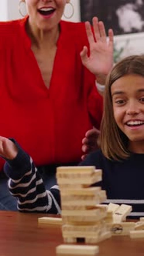 Child Plays Jenga with Family