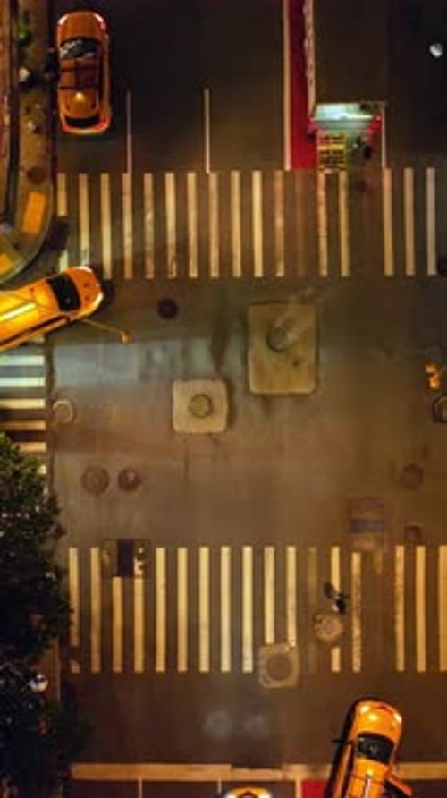 Descending view over the busy crossroads of New York. Well-lit street with numerous moving cars.