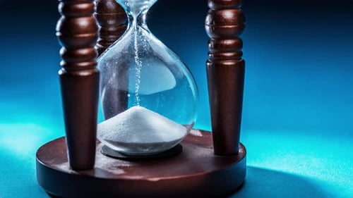 Hourglass with white sand in the concept of fast current time.