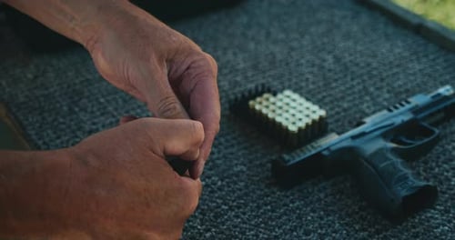 Loading Bullets Into Pistol Magazine on Carpeted Shooting Table