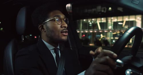 Young Man Driving Car at Night in City