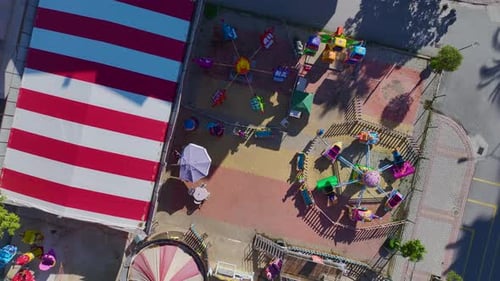Aerial Video Aerial View of a Small Park with Worn Swings and Simple Attractions