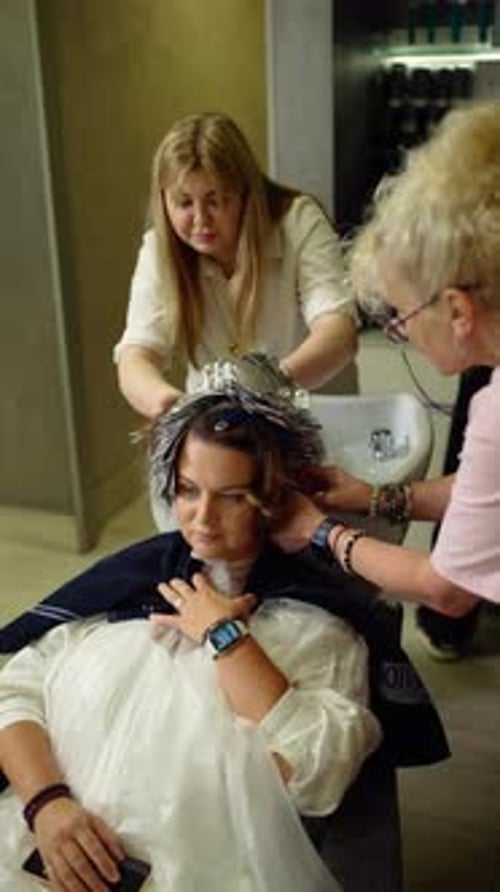 Woman at Hair Salon Getting Hair Colored by Stylists