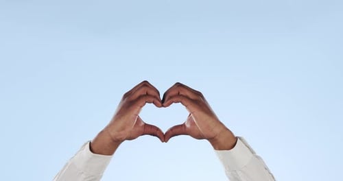 Hands Forming Heart Shape Against Blue Sky