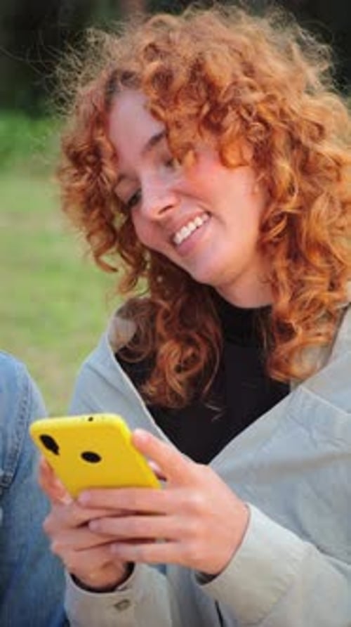 Smiling woman using her cellphone outside during the day