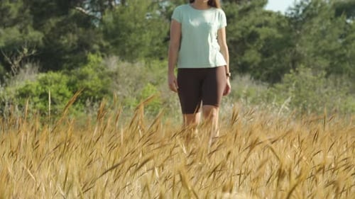 Woman Walking Through Tall Golden Grass