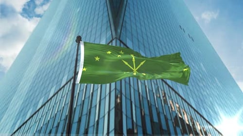 Green Flag with Yellow Stars Waving Against Modern Skyscraper
