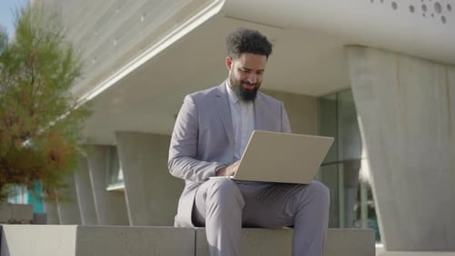 Man in Suit Working on Laptop Outdoors