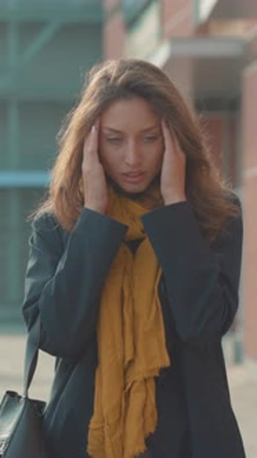 Une femme stressée est à l'extérieur tout en portant un foulard jaune vif incarnant ses émotions