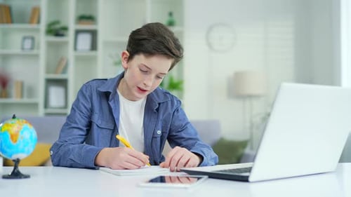 Focused Boy Studying at Desk with Laptop