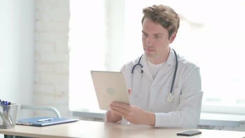 Young Doctor Browsing Internet on Tablet in Clinic