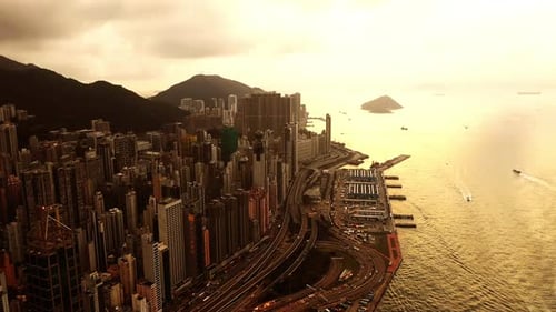 Ocean, buildings and aerial of city at sunset with roads, streets and skyscrapers in Hong Kong