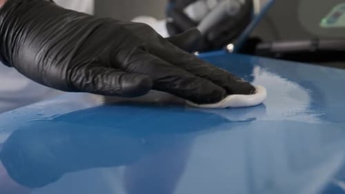 Hand Wiping Blue Car Surface With Applicator