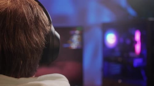 Young Man Has a Video Game Stream or Podcast in Neon Room Male Gamer Playing Online Video Games on