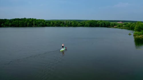 Young Man Paddleboarding on Scenic Lake