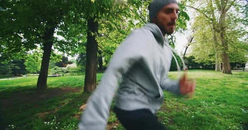 Slow motion of young man is having fun to listening to the music and dancing in green city park on