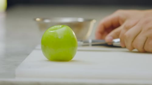 Chef peeling a green on a board in close-up.