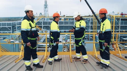 Un equipo de metalúrgicos construye un ingeniero industrial que habla sobre una planta de perforación de petróleo y gasolina para la construcción