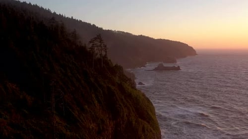 Aerial orbit and revealing beautiful landscape of the Oregon Coast during golden hour at sunset.
