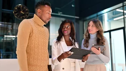 Multiracial group of workers in an office discussing business using tablets