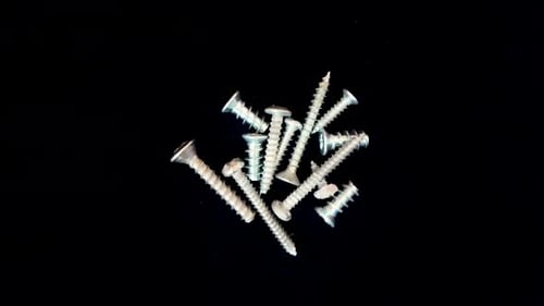 Metal screws rotating in sync against a black background, industrial and precise motion