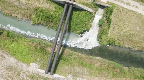 Aerial top down of industrial waste water mixing with water canal and flowing towards river.