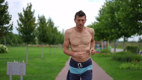 Front View Motivated Fit Sportsman Running Outdoors in Slow Motion Looking Around Leaving