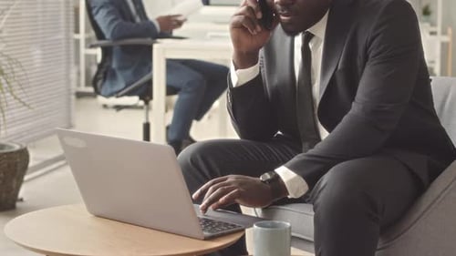 Young Adult Typing on Laptop During Phone Call