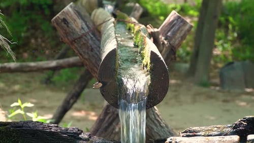 Clear fresh water flowing through open wooden pipes filling wooden water mill for milling wheat and