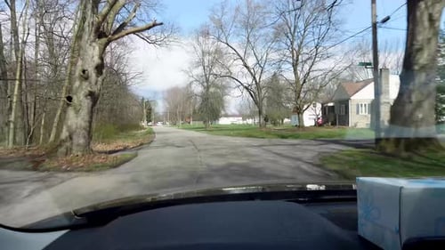 A peaceful shot capturing the experience of driving through a quiet suburban neighborhood, with bare