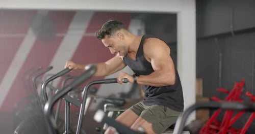 Exercising on stationary bike, man focusing on intense cardio workout in gym