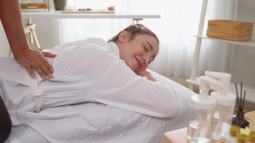 Schöne Frau im Bademantel bei einer Rückenmassage im Beauty Spa.