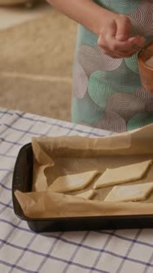 Girl sprinkles sugar on cookies in home kitchen