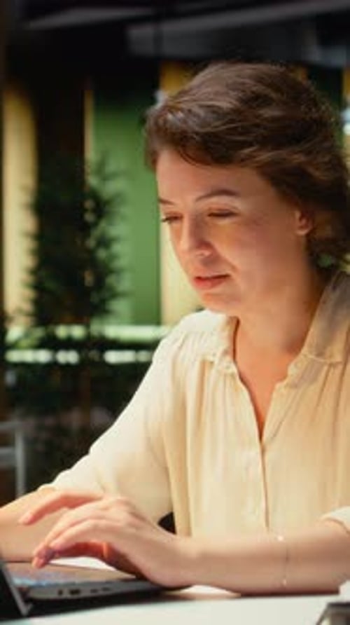 Thoughtful Woman Working on Laptop in Modern Office